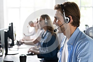 Young handsome male customer support phone operator with headset working in call center