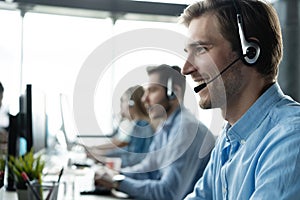 Young handsome male customer support phone operator with headset working in call center