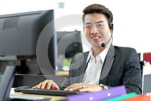 Young handsome male customer support phone operator with headset working in call center. Professional operator concept