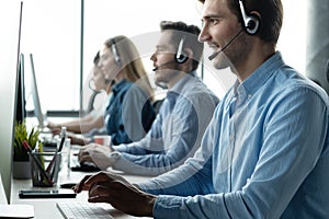 Young handsome male customer support phone operator with headset working in call center