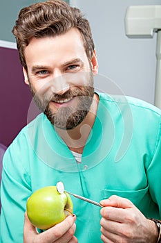 Young handsome male doctor smiling with white teeth holding apple