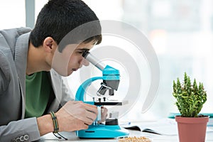 Young handsome male student using microscope