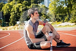 Young handsome man athlete resting at the stadium