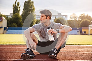 Young handsome man athlete resting with water bottle