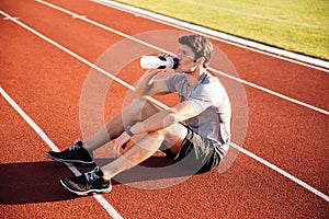 Young handsome man athlete resting with water bottle