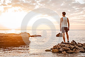 Young handsome man athlete standing at the rocky beach