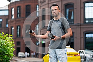 Young Handsome Man With Backpack Launching Drone Quadcopter at Urban Stlilysh Contemporary Cityscape. Modern device