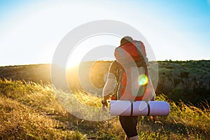 Young handsome man with backpack traveling in canyon at sunset.