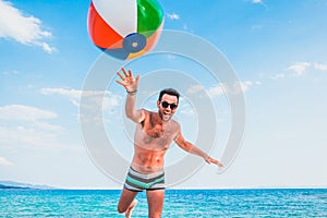 Young handsome man at the beach trowing the ball