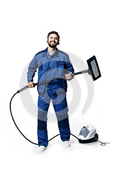 Young handsome man with a beard in a blue working uniform for cleaning rooms listens to music with headphones smiling