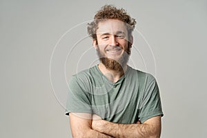 Young handsome man with beard and curly hair in olive t-shirt looking at camera isolated on white background. Portrait