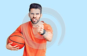 Young handsome man with beard hoilding basketball ball annoyed and frustrated shouting with anger, yelling crazy with anger and