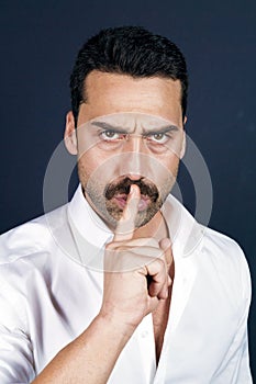 Young handsome man with beard and mustache showing hush sign