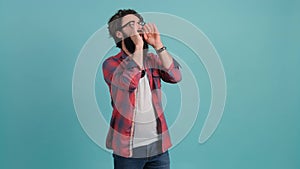 Young handsome man with beard shouting angry out loud with hands over mouth.