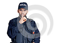 Young handsome man with beard wearing police uniform asking to be quiet with finger on lips
