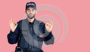 Young handsome man with beard wearing police uniform relax and smiling with eyes closed doing meditation gesture with fingers