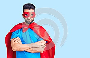 Young handsome man with beard wearing super hero costume skeptic and nervous, disapproving expression on face with crossed arms