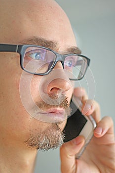 Young handsome man in black glasses is talking on the phone. Closeup portrait of a man. Manager, office worker, talking on the