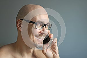 Young handsome man in black glasses is talking on the phone, smiling. Closeup portrait of a man. Manager, office worker, talking
