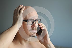 Young handsome man in black glasses is talking on the phone and is surprised. Big problems, bad news. Closeup portrait of a man.