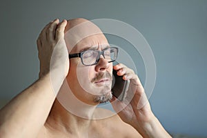 Young handsome man in black glasses is talking on the phone and is surprised. Big problems, bad news. Closeup portrait of a man.