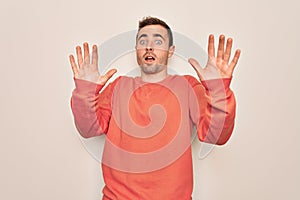 Young handsome man with blue eyes wearing casual sweater standing over white background afraid and terrified with fear expression