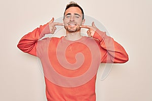 Young handsome man with blue eyes wearing casual sweater standing over white background smiling cheerful showing and pointing with