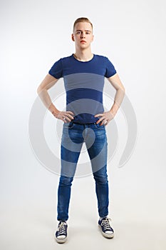 Young handsome man in blue shirt and jeans poses