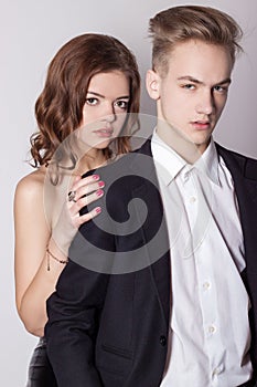 Young handsome man in a business suit and a white shirt in official style with beautiful girl, couple in love in the Studio