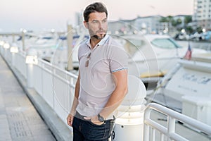 Young handsome man in classik polo t-shirt on the street. Handsome confident stylish hipster model posing outside. Rich