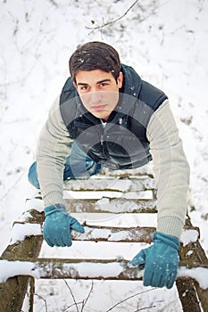 young handsome man climbing upwards wooden ladder