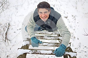 Young handsome man climbing upwards wooden ladder