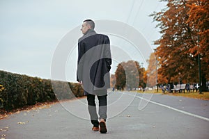 Young handsome man in coat. Fashionable well dressed man posing in stylish coat. Confident and focused boy outdoor at autumn.