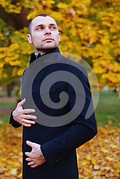 Young handsome man in coat. Fashionable well dressed man posing in stylish coat. Confident and focused boy outdoor at autumn.
