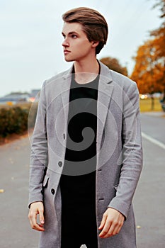 Young handsome man in coat. Portrait of fashionable well dressed man posing in grey stylish coat. Confident and focused boy