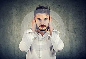 Young man covering ears avoiding noise photo