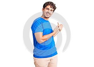 Young handsome man with curly hair wearing casual clothes inviting to enter smiling natural with open hand