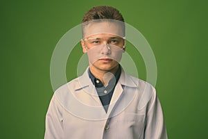 Young handsome man doctor wearing protective glasses against green background