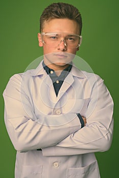 Young handsome man doctor wearing protective glasses against green background