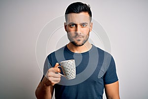 Young handsome man drinking a cup of hot coffee over white isolated background with a confident expression on smart face thinking