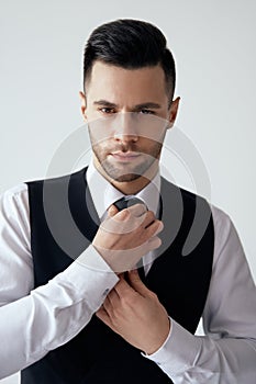 Young handsome man in elegant suit adjust his necktie