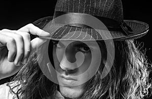 Young handsome man emotional pose with hat. Portrait of handsome young serious confident young guy with long hair in hat