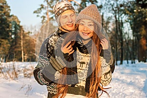 A young handsome man of European appearance and a young Asian girl in a park on the nature in winter