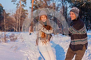 A young handsome man of European appearance and a young Asian girl in a park on the nature in winter