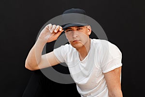 Young handsome man in a fashionable black cap and white T-shirt