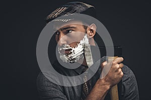 Young handsome man in flat cap shaving his beard