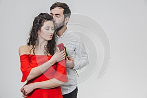 A young, handsome man gently covers his beautiful wife. During this time, one red rose. The girl is dressed in a red