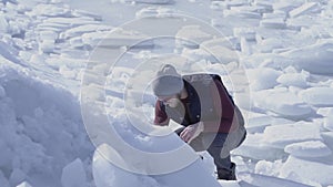 Young handsome man geologist searched something in cold ice snowing glacier behind the winter sea. Slow motion