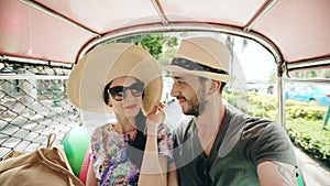 Young handsome man in hat with his girlfriend ride on traditional thai bus songteo. Couple travel Thailand during their