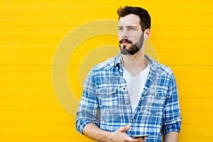 Young handsome man with headphones on yellow wall